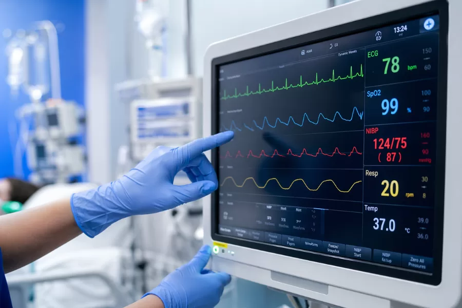 Profissional de enfermagem monitorando sinais vitais em equipamento hospitalar na UTI ou emergência
