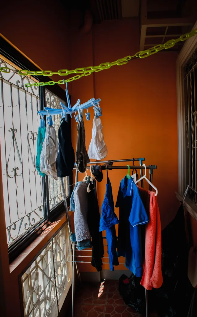Ropa colgada para secarse en un tendedero interior cerca de una ventana con entrada de luz natural